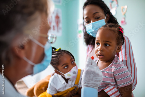 Close up of doctor taking sample from nose. Focus on little girl patient
