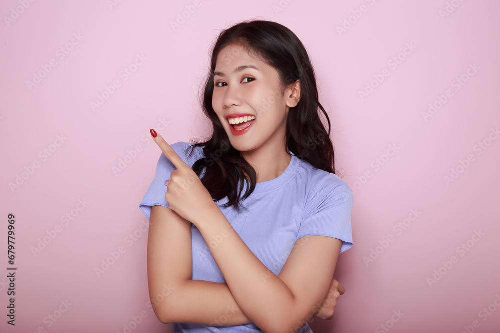 Standing and pointing happily, Portrait of a beautiful young woman in a light pink background, happy and smile, posting in stand position, Portrait of a friendly young woman smiling happily. Standing and pointing happily, Portrait of a beautiful young woman in a light pink background, happy and smile, posting in stand position, Portrait of a friendly young woman smiling happily.