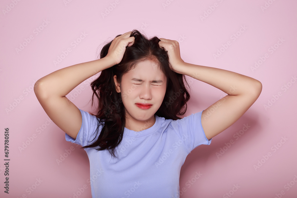 Asian woman making a stressed expression Standing alone on a light pink background. Beautiful young woman is feeling stressed.