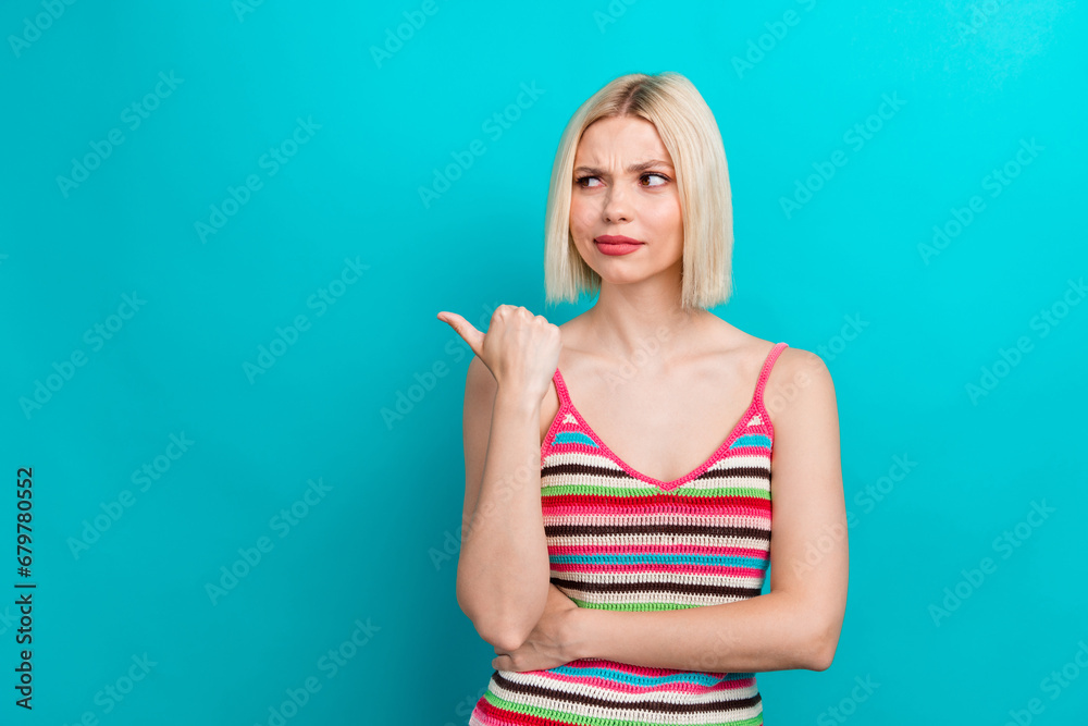 Photo portrait of pretty young girl point look skeptical empty space wear trendy striped outfit isolated on cyan color background