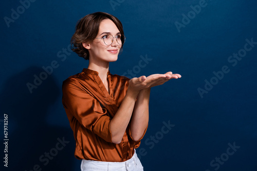 Photo portrait of pretty young girl palms hold promo empty space dressed stylish brown blouse isolated on dark brown color background