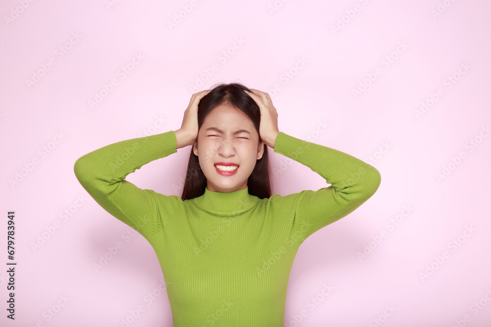 Asian woman making an angry expression, Portrait of a young woman in a light pink background. Asian woman making an angry expression, Portrait of a young woman in a light pink background.