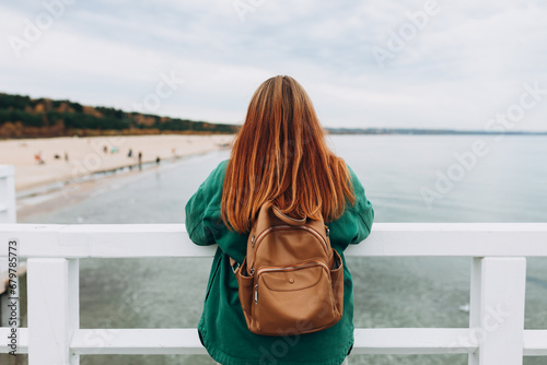 Back view of stylish Woman with backpack relaxing near sea. Freedom and active lifestyle concept. High quality photo. Idea of power, nature, solitude.