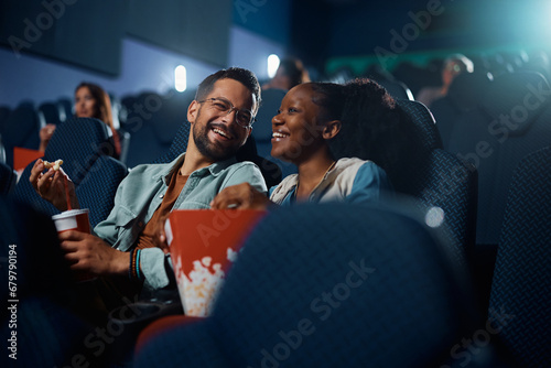 Cheerful couple has fun during movie projection in cinema. photo