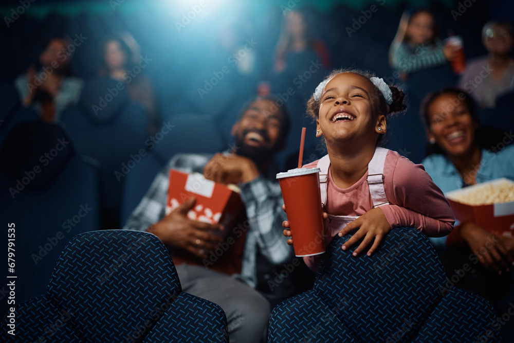 Φωτογραφία Cheerful black little girl watching movie in theater.