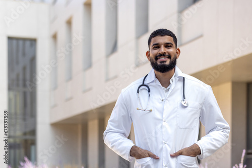 Portrait of a Latin American male doctor, nurse, veterinarian standing outside the clinic on the street in a white coat and smiling and confidently looking at the camera photo