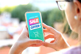 Young woman holding a smartphone a sale offer advertising on the screen. Marketing, discount, cell phone, internet ads.