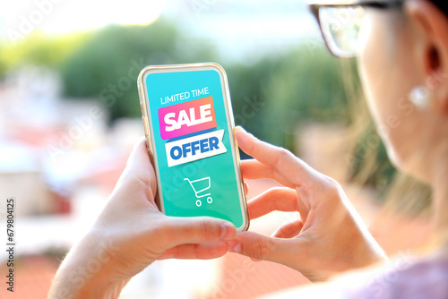 Young woman holding a smartphone a sale offer advertising on the screen. Marketing, discount, cell phone, internet ads.