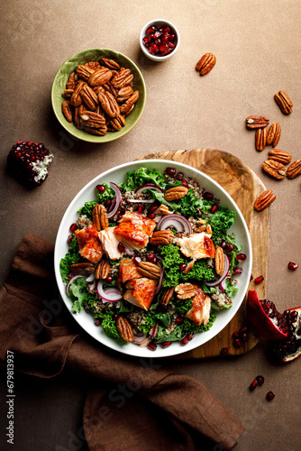Salmon superfood salad with grilled fish, kale, quinoa, pecan nuts, red onion and pomegranate. Top view