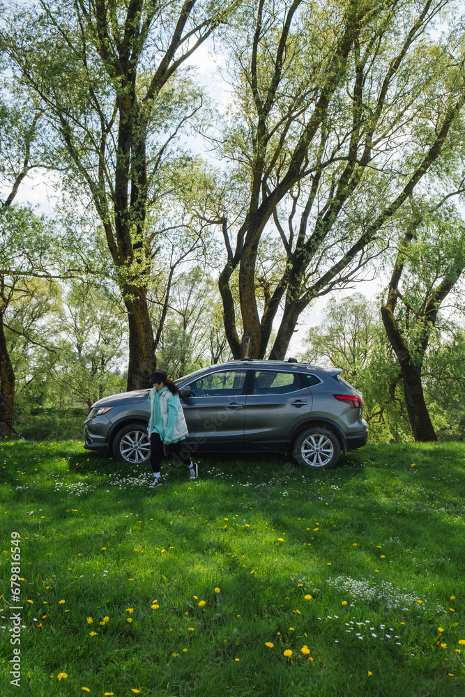 a woman runs from a parked car on a green lawn in nature