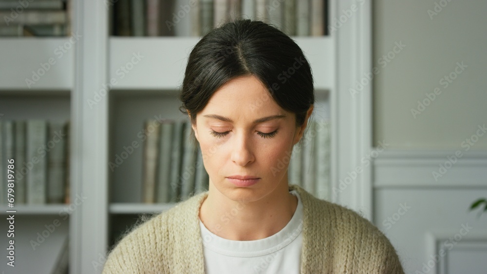 Close-up of upset girl sad tense sitting at home in living room with offended offended expression on her face, worrying about problems. Depressed Frustrated Sad worried young woman. Close up view Close-up of upset girl sad tense sitting at home in living room with offended offended expression on her face, worrying about problems. Depressed Frustrated Sad worried young woman. Close up view