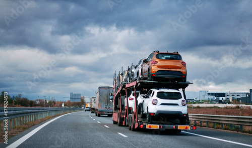Car carrier trailer truck with brand new off-road vehicles for sale. New car delivery. Car transporter trailer loaded with many new cars for the customers. Two-level modular hydraulic semi-trailer