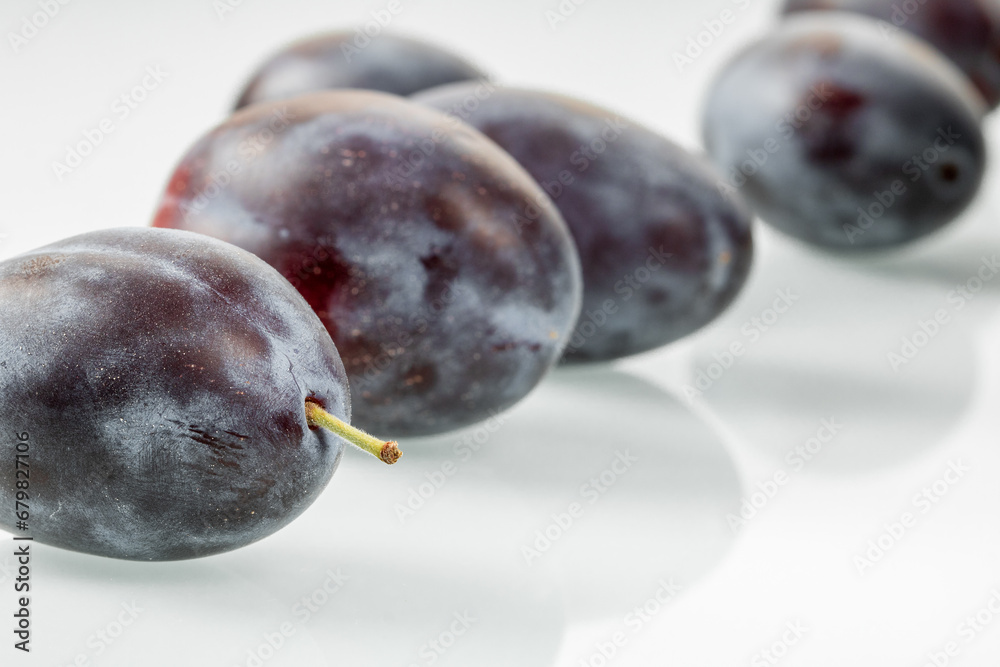 Bunch of ripe dark plums on a white background