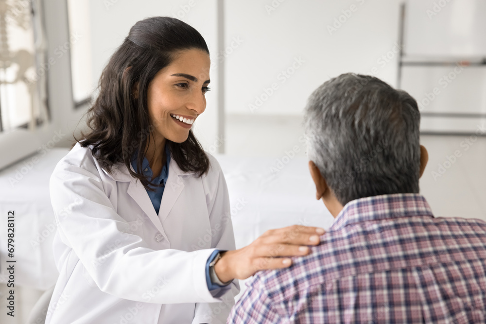 Happy young doctor woman enjoying medical job, giving support to older patient, talking to man for healthcare examination, checkup, touching shoulder with support, sympathy Happy young doctor woman enjoying medical job, giving support to older patient, talking to man for healthcare examination, checkup, touching shoulder with support, sympathy