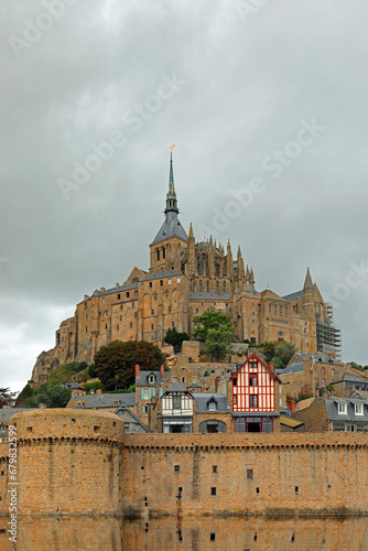 famous ancient Mont Saint Michel abbey above the hill during the tide and the city wall with reflection on the water