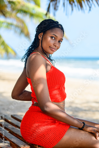 A portrait of a young african lady relaxing on a bench at a beach 