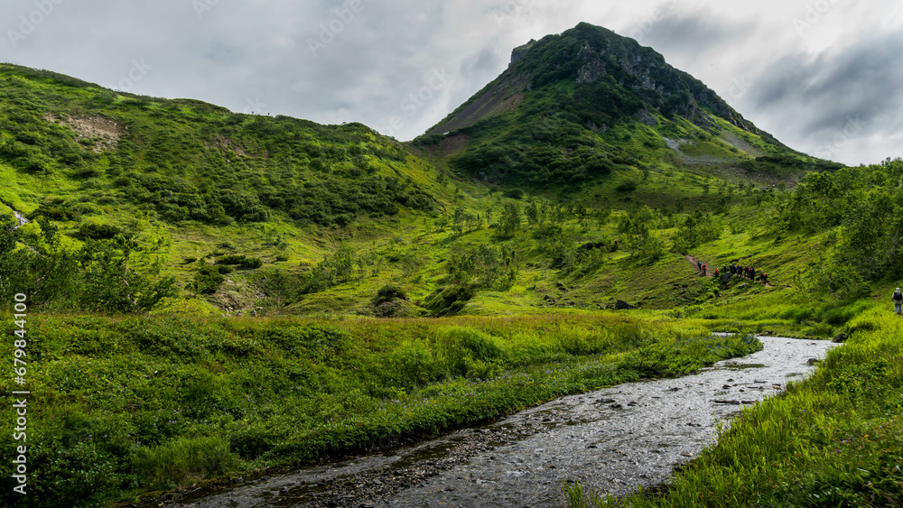 The scenic river goes through the Vachkazhets valley at Kamchatka krai, Russia, with beautiful mountains and grass fields around.