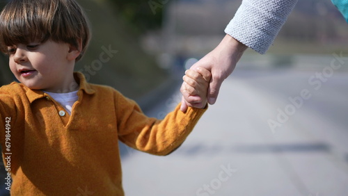 Child holding mother hand walking forward  front view close-up face of small boy bonding time with parent