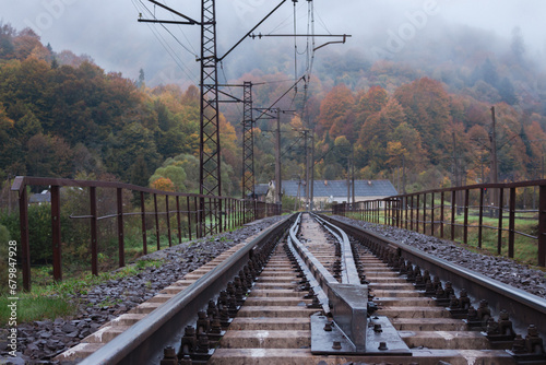Railway in the mountains. Railroad tracks in autumn mountains. Railroad in foggy morning landscape. Transportation industry. Travel destinations concept. Logistic infrastructure. 