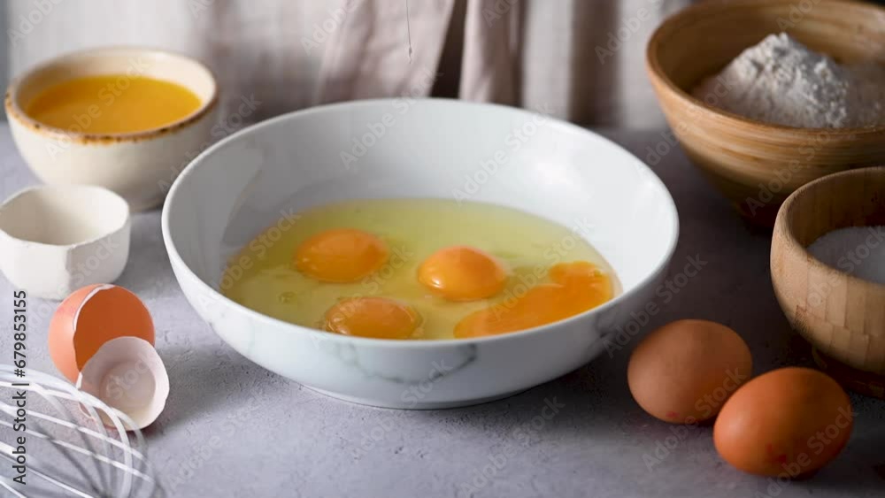 Female hands break raw chicken egg in white bowl. Cooking, baking concept. Female hands break raw chicken egg in white bowl. Cooking, baking concept.
