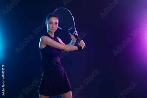 Tennis player with racket on tournament. Girl athlete with tenis racket on court with neon colors. Sport concept. Download a high quality photo for design of a sports app or tour events. © Mike Orlov