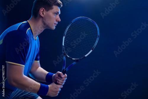 Tennis player with racket closeup. Man athlete playing isolated on blue background. © Mike Orlov