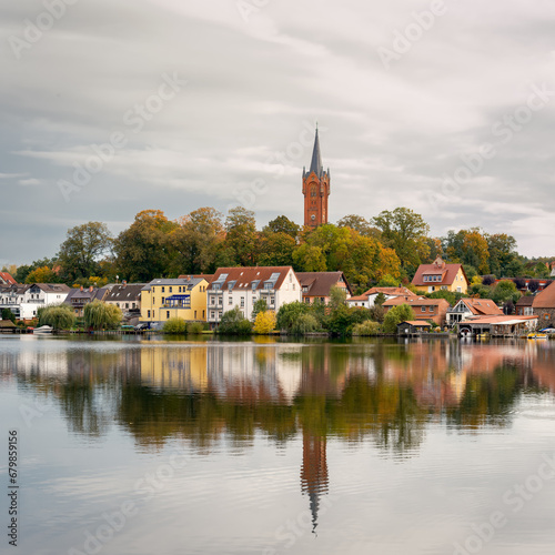 Die Skyline von Feldberg mit dem Turm der Stadtkirche spiegelt sich im Wasser des herbstlichen Haussee - Inschriften wurden retuschiert