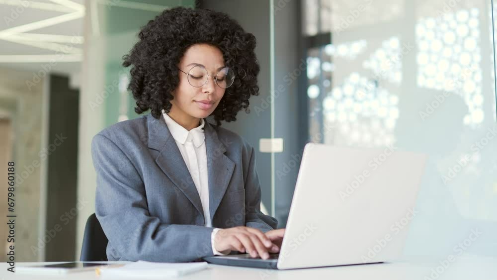 Young african american businesswoman in a suit typing on laptop while ...