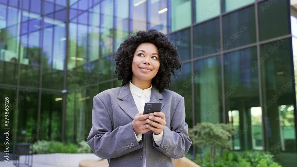 Young african american businesswoman in a suit is using smartphone ...