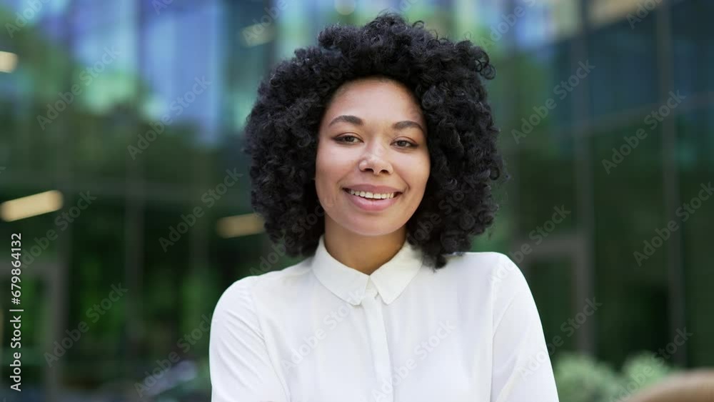 Close up portrait of a young happy african american female employee standing on the street near an office building. Smiling black woman looking at the camera. Headshot of a successful manager or agent Close up portrait of a young happy african american female employee standing on the street near an office building. Smiling black woman looking at the camera. Headshot of a successful manager or agent