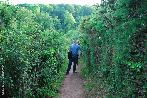 Man is standing on a footpath in a lush green environment 
