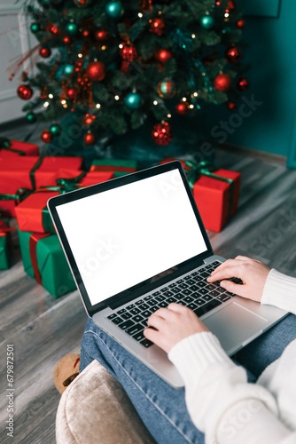 Young woman work on laptop computer with blank display screen with mockup copy space. Modern home living room interior design. Christmas, New Year decorated workspace