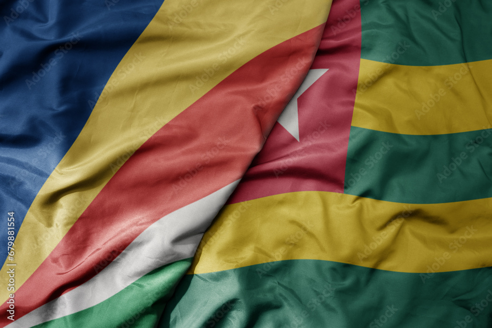 big waving national colorful flag of seychelles and national flag of togo .