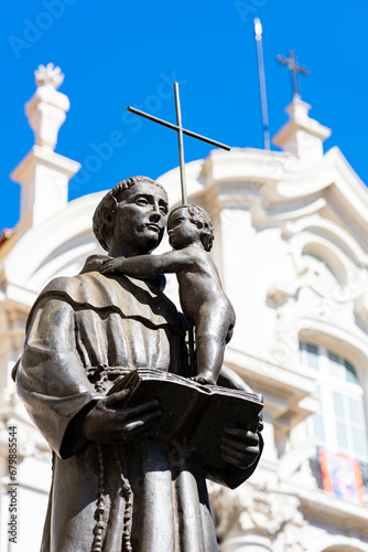 statue of santo antonio on the left side with the church of santo antonio in the background on the right side, lisbon.the statue is located in the center of santo antonio square between the church and