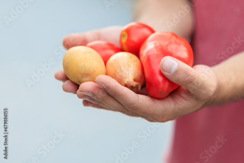 The guy's hand holds vegetables. Selective focus on hands with blurred background