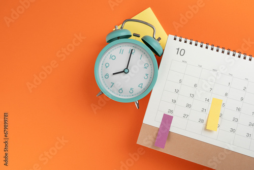 close up of calendar and alarm clock on the orange table background, planning for business meeting or travel planning concept photo