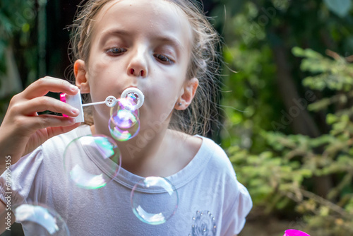 Little girl blowing soap bubbles. Child enjoying blowing soap bubbles