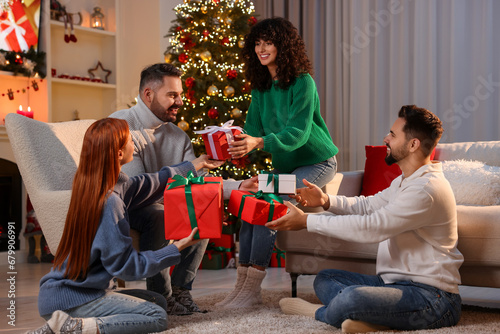 Christmas celebration. Happy friends exchanging gifts at home