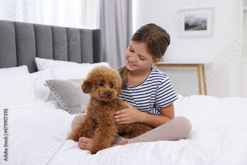 Little child with cute puppy on bed at home. Lovely pet