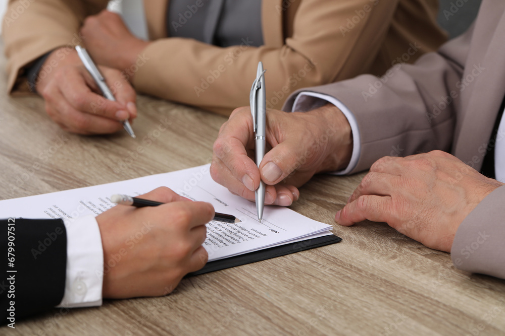 Manager showing client where he must to mark signature at light wooden table indoors, closeup Manager showing client where he must to mark signature at light wooden table indoors, closeup