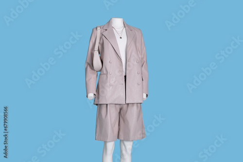 Female mannequin dressed in white t-shirt and stylish leather suit with accessories on light blue background