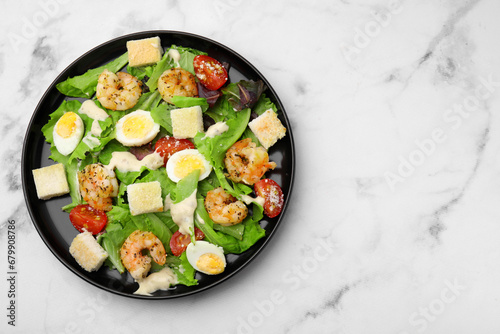 Delicious Caesar salad with shrimps on white marble table, top view. Space for text