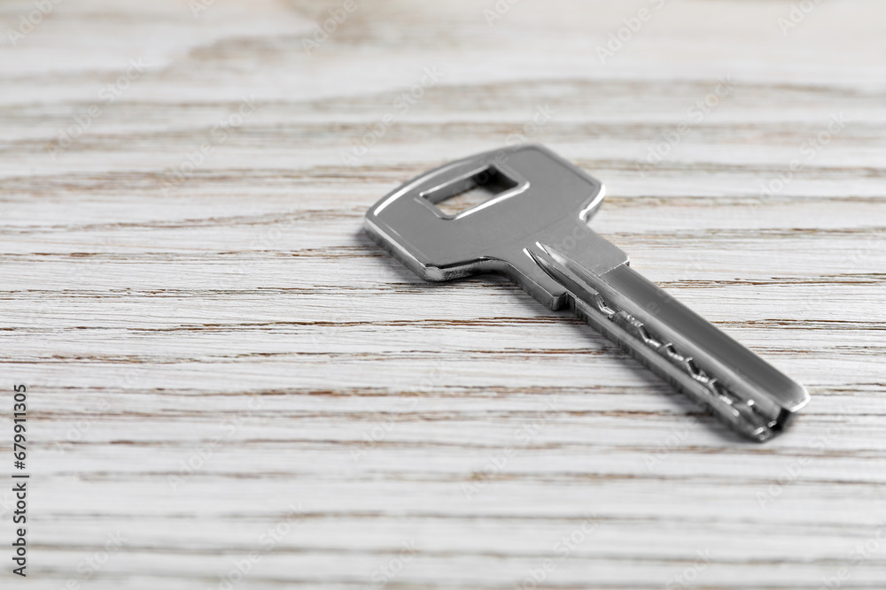One key on light wooden table, closeup. Space for text One key on light wooden table, closeup. Space for text