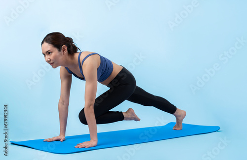 Asian woman in sportswear doing burpee on exercising mat as workout training routine. Attractive girl in pursuit of healthy lifestyle and fit body physique. Studio shot isolated background. Vigorous