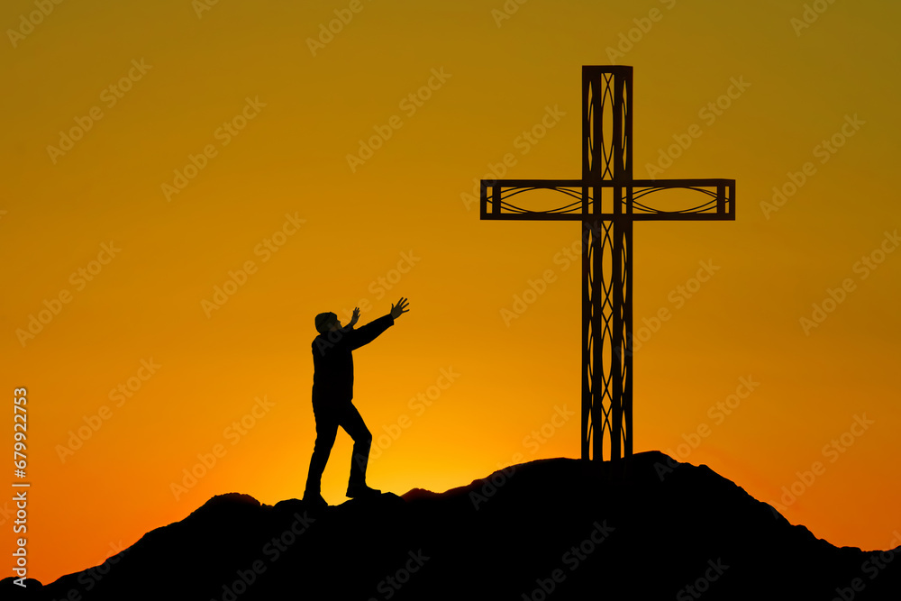 Man stands before a cross on a mountain