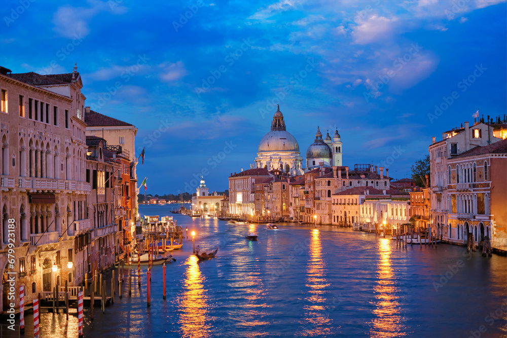 View of Venice Grand Canal with boats and Santa Maria della Salute church in the evening from Ponte dell'Accademia bridge. Venice, Italy