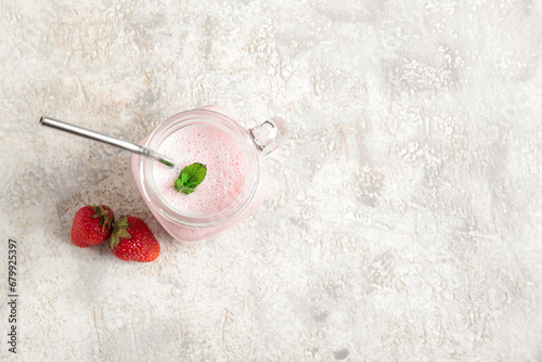 Mason jar of tasty strawberry smoothie on light background
