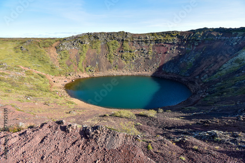People hike the rim of Kerid crater is a dormant volcano with a deep blue lake, formed after the volcano collapsed after an eruption 6000 years ago.