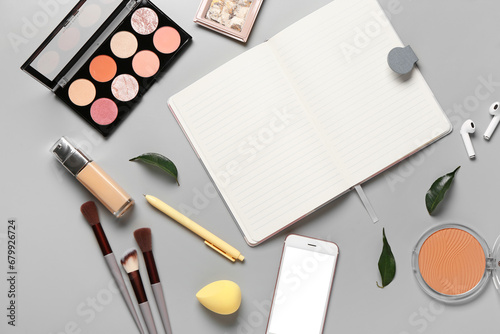Composition with makeup cosmetics, modern mobile phone and notebook on grey background