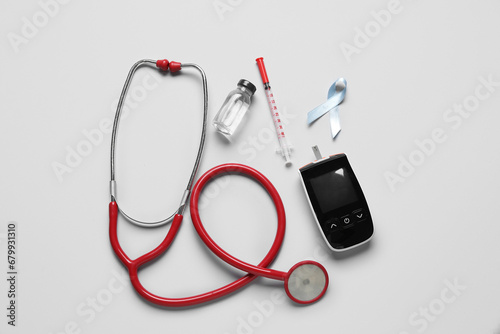 Awareness ribbon with insulin, glucometer and stethoscope on light background. Diabetes concept
